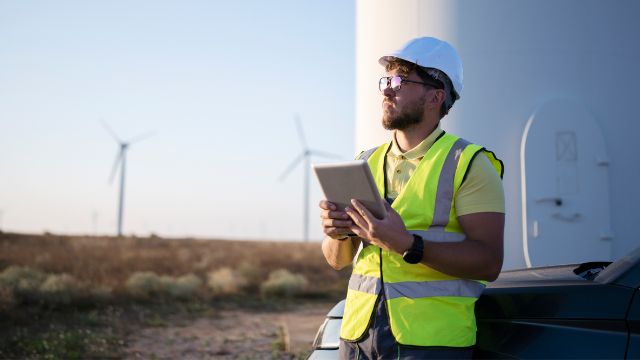 A field worker surveying a wind turbine