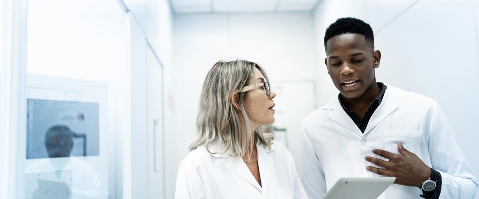 Colleagues in white lab coats discussing work