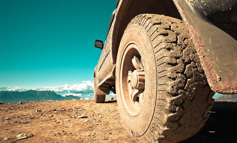 Muddy tire of an off-roading vehicle parked on a mountain side